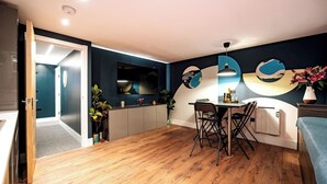 A modern kitchen with a built-in oven, a dining area with a table and chairs, and a large window with a view of the city. - The Nest: Luxury 16 person Apt w jacuzzi & parking (Blackpool)
