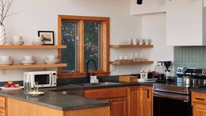 Una cucina moderna con mobili in legno, forno a microonde integrato, piano cottura in acciaio inossidabile e una finestra vista alberi.