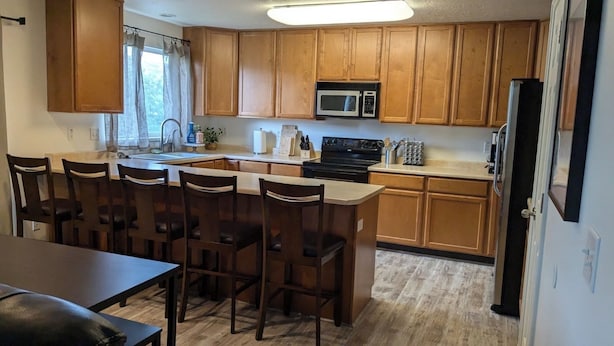 Une cuisine dotée de meubles en bois, d’un four à micro-ondes, d’une cuisinière et d’un coin repas avec des chaises et une table.