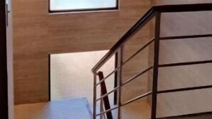 Un interior modern amb una finestra gran, parets de fusta i una escala amb barana metàl·lica.