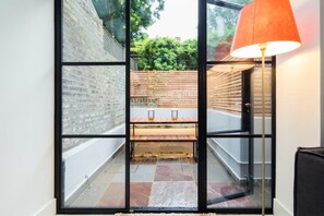 A modern interior with a glass partition, a wooden bench, and a red lamp. - Beautiful Separate Self Contained Garden Apartment (London)