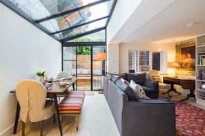 A compact living space with a dining area, a sofa, a desk, and a bookshelf. - Beautiful Separate Self Contained Garden Apartment (London)