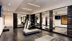 Une salle de sport moderne équipée de matériel d’exercice, dotée d’un mur miroir et d’un plancher en bois.