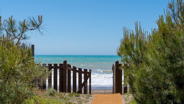 A wooden gate leading to a beach with clear blue water and a sandy path. - Villa Corallina 12, Emma Villas (Marina di Bibbona)