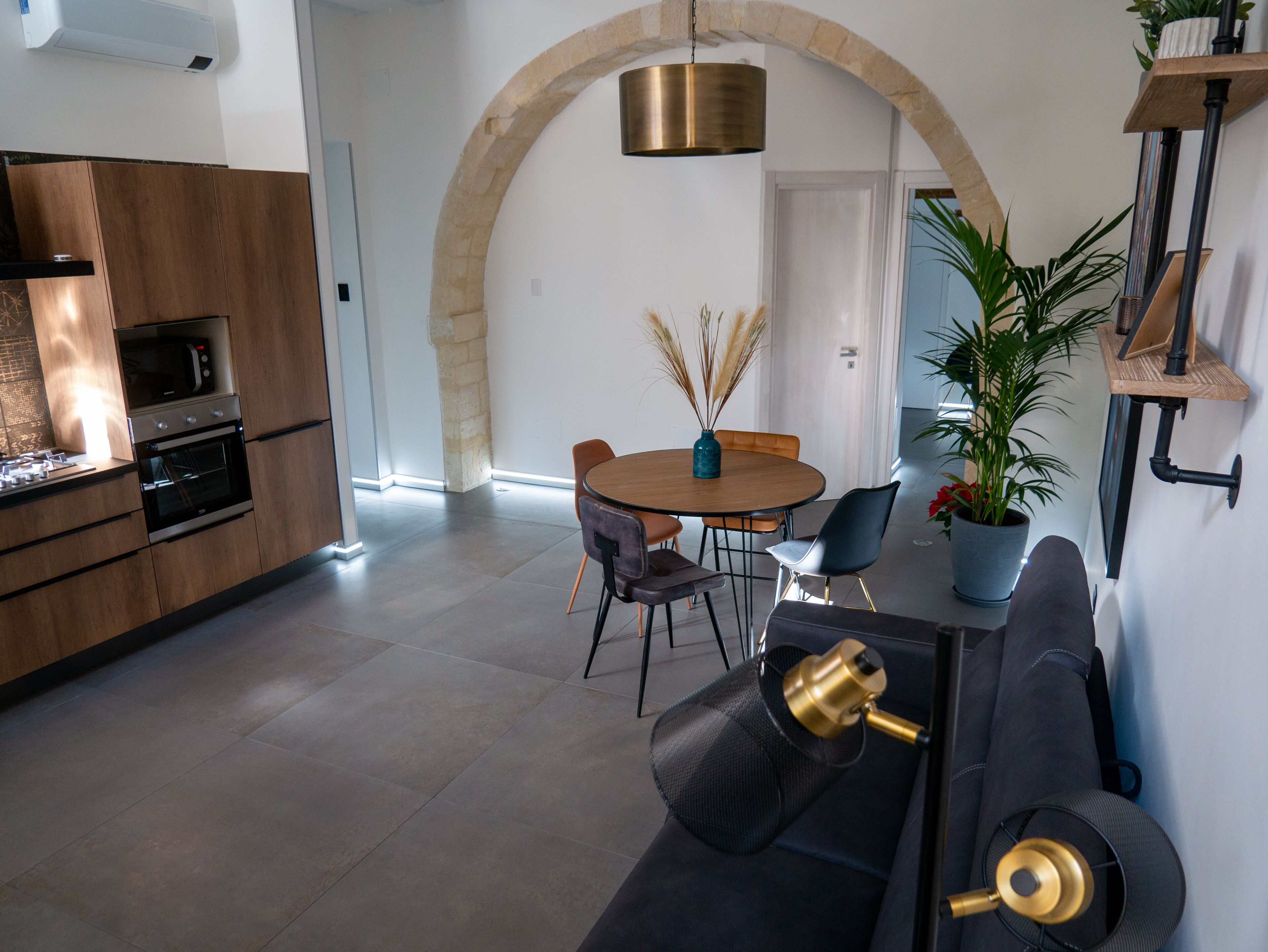 A modern kitchen with built-in appliances, a dining area with a round table and chairs, and a cozy seating area with a sofa and a side table.