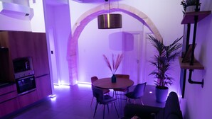 A modern kitchen with a microwave, oven, and built-in dishwasher. There is a dining area with a round table and chairs, and a potted plant. - Elegante Suite a piano terra di un palazzo storico del 1700 - Centro di Ortigia. (Siracusa)
