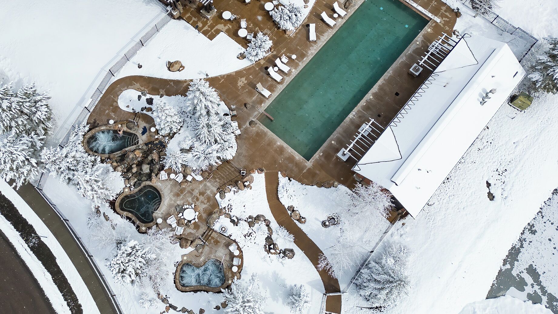 Vista aérea de un resort con piscina, jacuzzis y una zona cubierta.