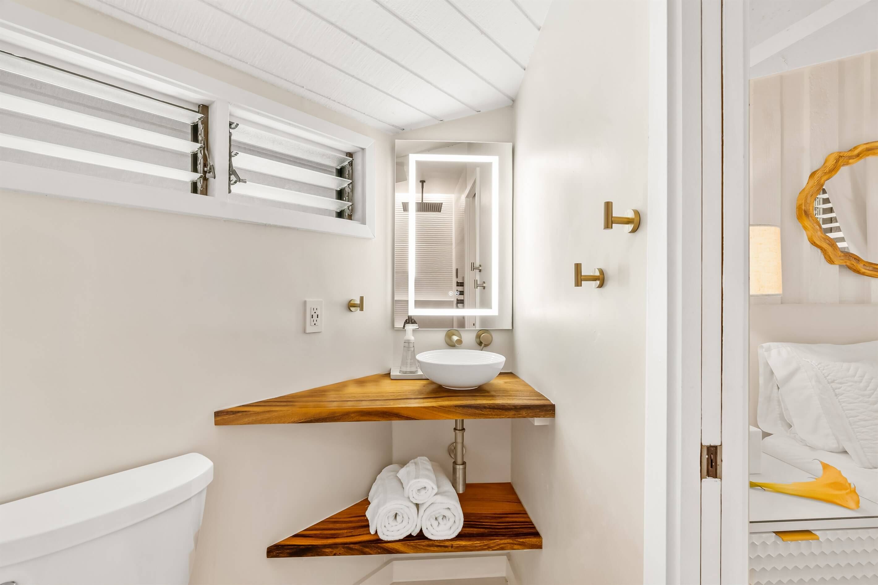 A modern bathroom with a wooden vanity, a white sink, and a mirror.