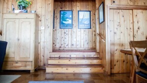 A wooden interior with a staircase, a cabinet, and two framed signs. - Big Glen Lake - Beechwood Cottage (Glen Arbor)