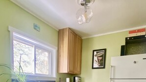 Eine Küche mit Holzausstattung, einem weißen Kühlschrank, einem Fenster und einem Fliesenboden.