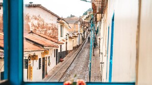 Una calle estrecha flanqueada por edificios, una vía de tren y un marco de puerta azul en primer plano.