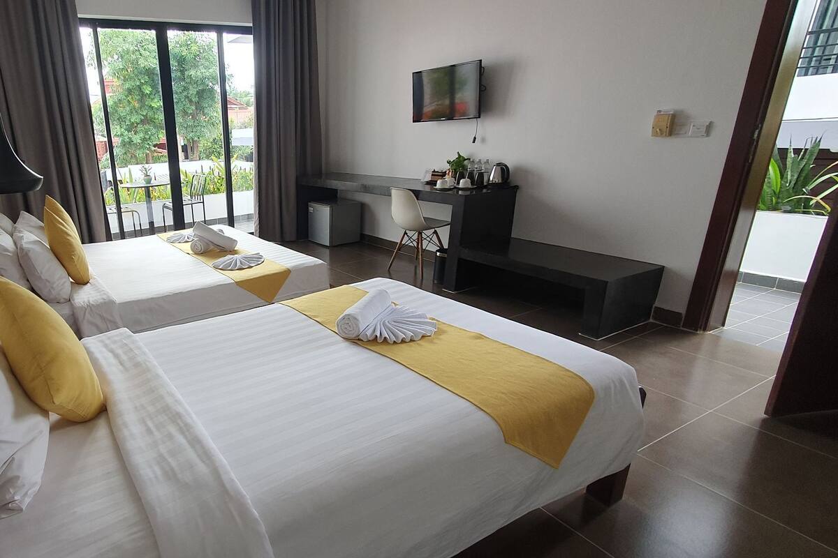 Une chambre d’hôtel avec deux lits, un bureau, une télévision et une vue sur l’extérieur.