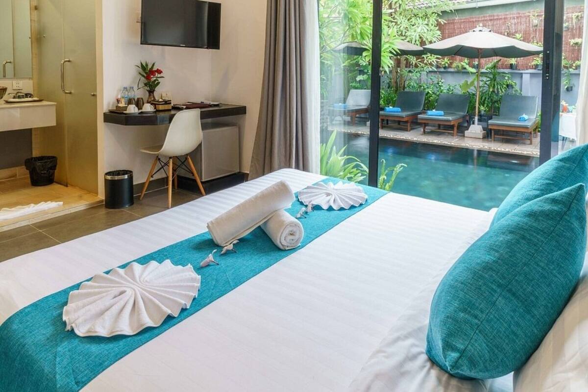 Une chambre d’hôtel équipée d’un lit, d’un bureau, d’une télévision et offrant une vue sur l’espace extérieur de la piscine.