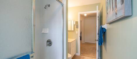 Une salle de bain avec douche, toilettes et lavabo.