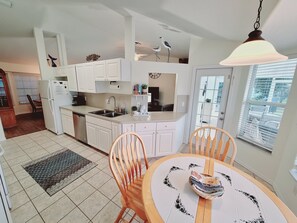 A modern kitchen with white cabinets, a dining table with chairs, and a hanging light fixture. - ☆☀︎❀Coastal Retreat! Heated Pool, Boat/RV Parking Double Lot, 3 miles to Beach! (Sebastian)