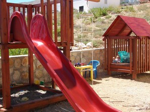 Children can play and explore in this fun play area featuring a slide, playhouse, and toys.