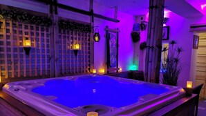 A hot tub with a wooden deck, surrounded by a wooden fence, and illuminated by purple lighting. - Escape with Rooftops" with PAID OPTION "JACCUZZI - SAUNA (Fécamp)