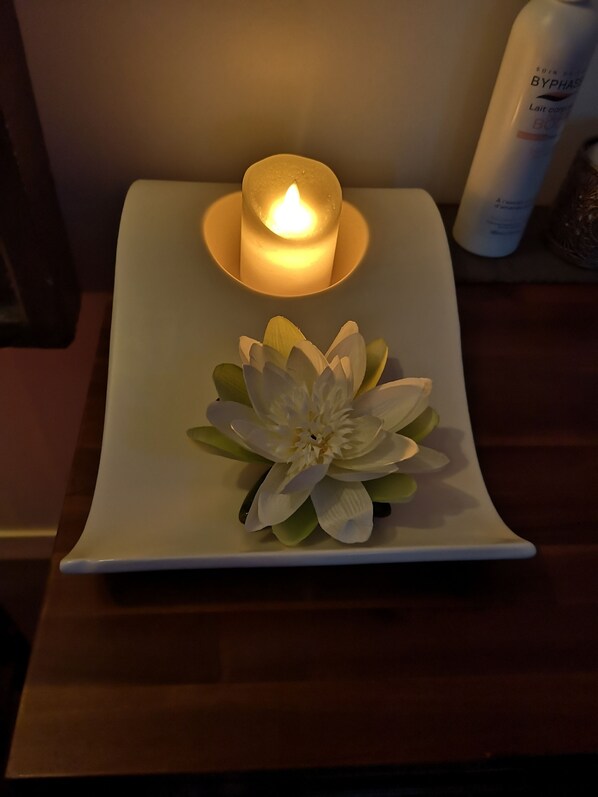 A white rectangular tray with a lit candle and a white flower arrangement on a wooden surface. - Escape with Rooftops" with PAID OPTION "JACCUZZI - SAUNA (Fécamp)