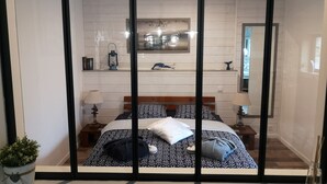 A bedroom with a bed, bedside tables, a mirror, and a potted plant. - Escape with Rooftops" with PAID OPTION "JACCUZZI - SAUNA (Fécamp)
