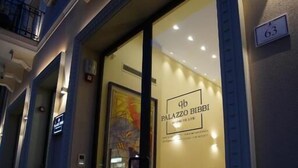 Hotellin sisäänkäynti, jossa on lasiovi, ja seinässä on kyltti, jossa lukee ”Palazzo Bibbi”, sekä numero ”63”.