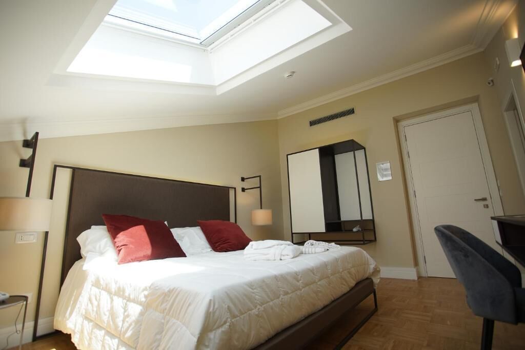 Une chambre d’hôtel comprenant un lit, un bureau, une chaise, une armoire et une fenêtre de toit.