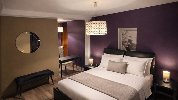 A modern bedroom with a bed, bedside tables, a bench, a desk, and a hanging light fixture. - le Flaubert (Villenauxe-la-Grande)