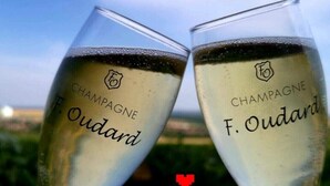 Two champagne glasses with the brand name "F. Oudard" and a logo, set against a blurred outdoor background. - le Flaubert (Villenauxe-la-Grande)