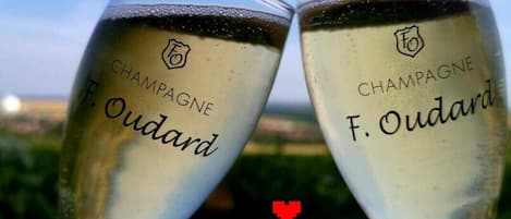 Dos copas de champán con el nombre de marca "F. Oudard" y un logotipo, sobre un fondo exterior desenfocado.