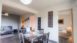 A modern dining area with a round table, chairs, and a chandelier. There are two blackboards with text on the walls. - Apartment in the maquis facing the sea, 5mm from the beach and shops (Cargèse)