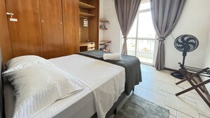Ein Hotelzimmer mit Bett, Schreibtisch, Kleiderschrank und Ventilator.