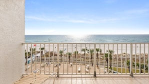 Un balcon avec vue sur une plage et l’océan.