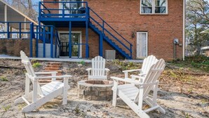 A brick building with a blue staircase and a covered outdoor seating area with Adirondack chairs. - Casa Azul: Tranquility + Fire Pit + Gameroom + Peace (Fayetteville)