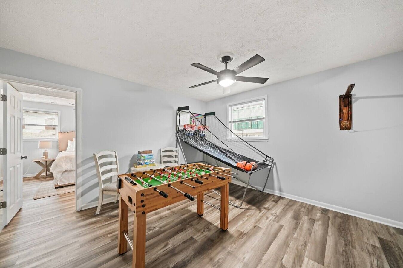 A room with a foosball table, a ceiling fan, and a small basketball hoop.