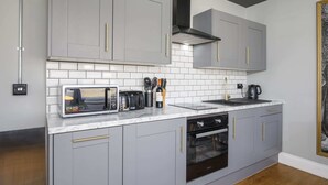 A modern kitchen with grey cabinets, a built-in microwave, a coffee maker, and a stove.