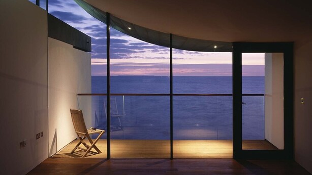 A room with a large window overlooking the sea, a wooden floor, and a single chair. - 2: Apartment with Magnificent Sea Views (Westward Ho!)