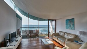 A modern living room with a large glass door leading to a balcony overlooking the sea. - 2: Apartment with Magnificent Sea Views (Westward Ho!)