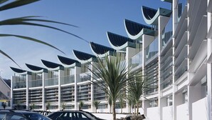 A modern building with a curved facade, a rooftop pool, and a pathway leading to the entrance. - 2: Apartment with Magnificent Sea Views (Westward Ho!)