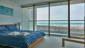 A bedroom with a large bed, a view of the beach, and a balcony. - 2: Apartment with Magnificent Sea Views (Westward Ho!)