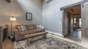 Una sala de estar con un sofá, una mesa de centro, una lámpara y un cuadro en la pared.