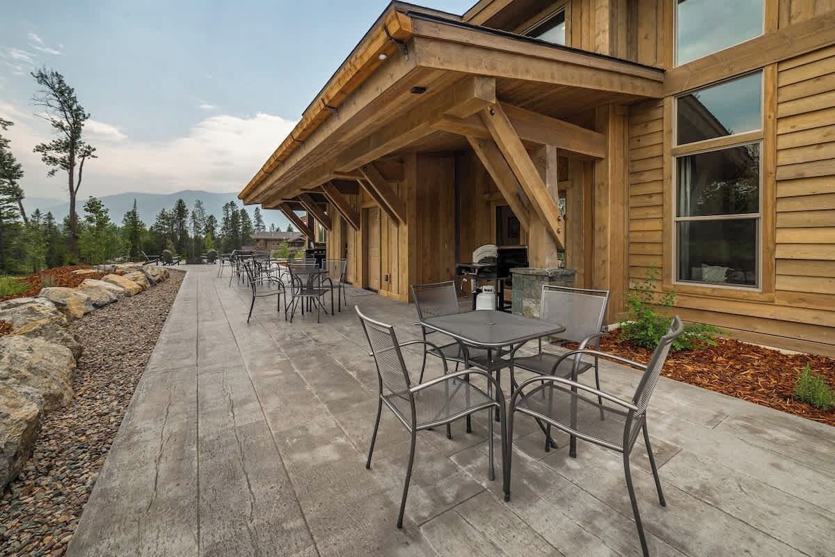 A wooden building with a covered patio area featuring outdoor seating and a grill.