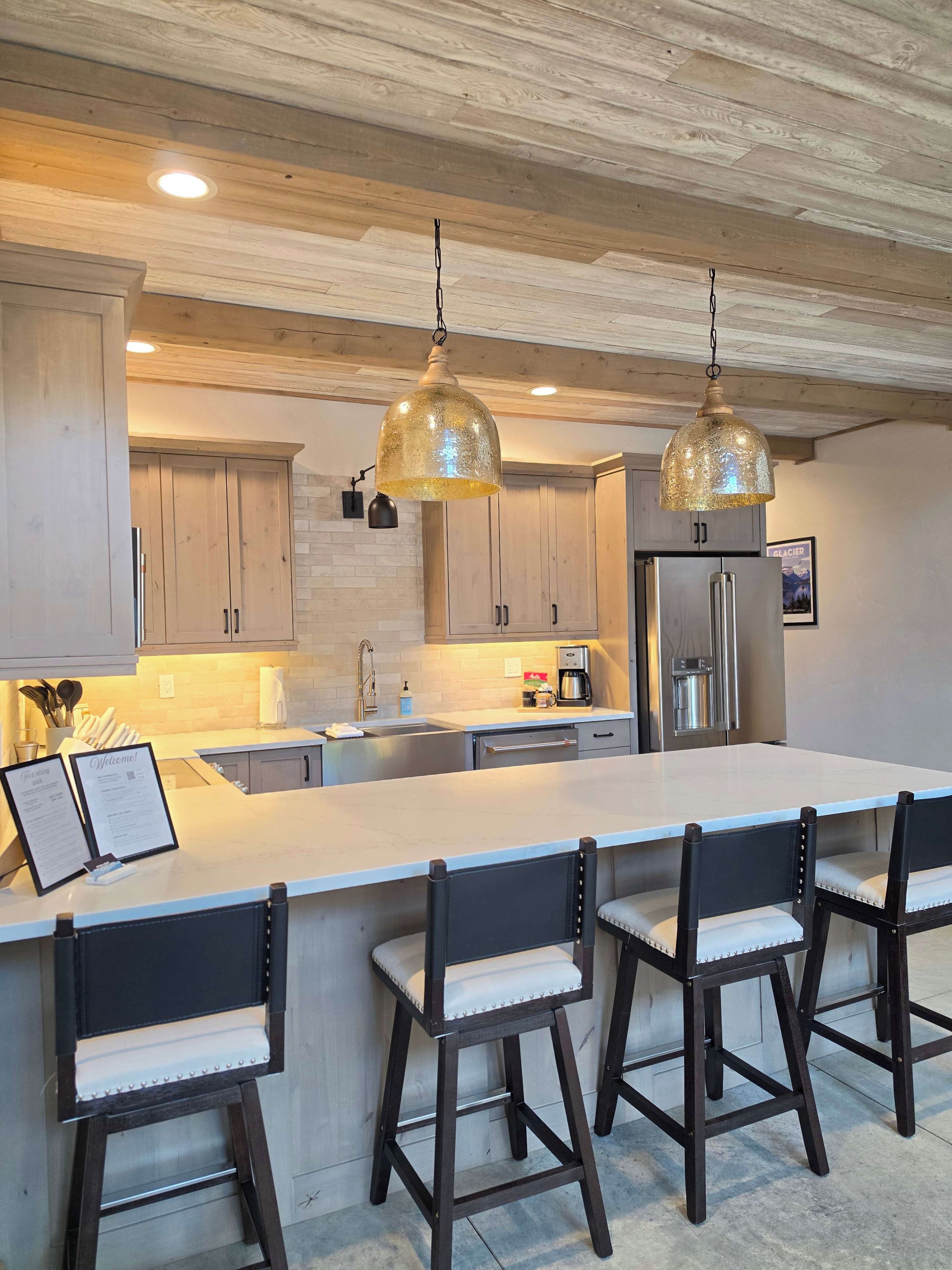 A modern kitchen with a large island, bar stools, and stainless steel appliances.