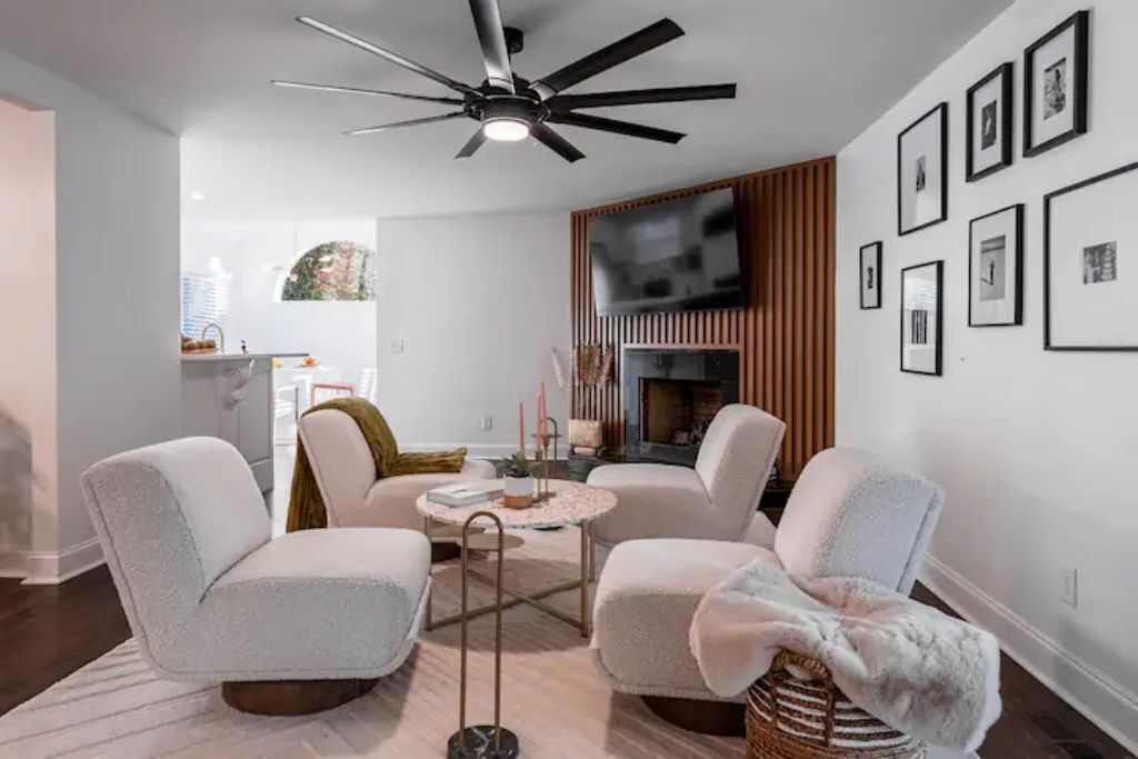 A modern living room with a ceiling fan, a fireplace, and framed pictures on the wall.