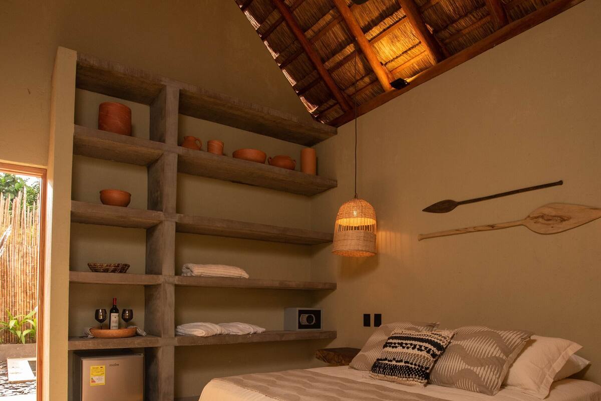 A bedroom with a bed, shelves, a ceiling fan, and a woven light fixture.