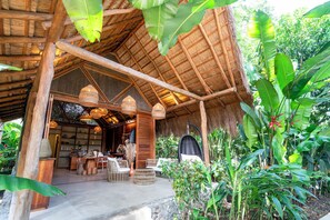 A rustic wooden structure with a thatched roof, wicker furniture, and hanging wicker lamps. - Nativa Refugio Escondido (Sopetrán)