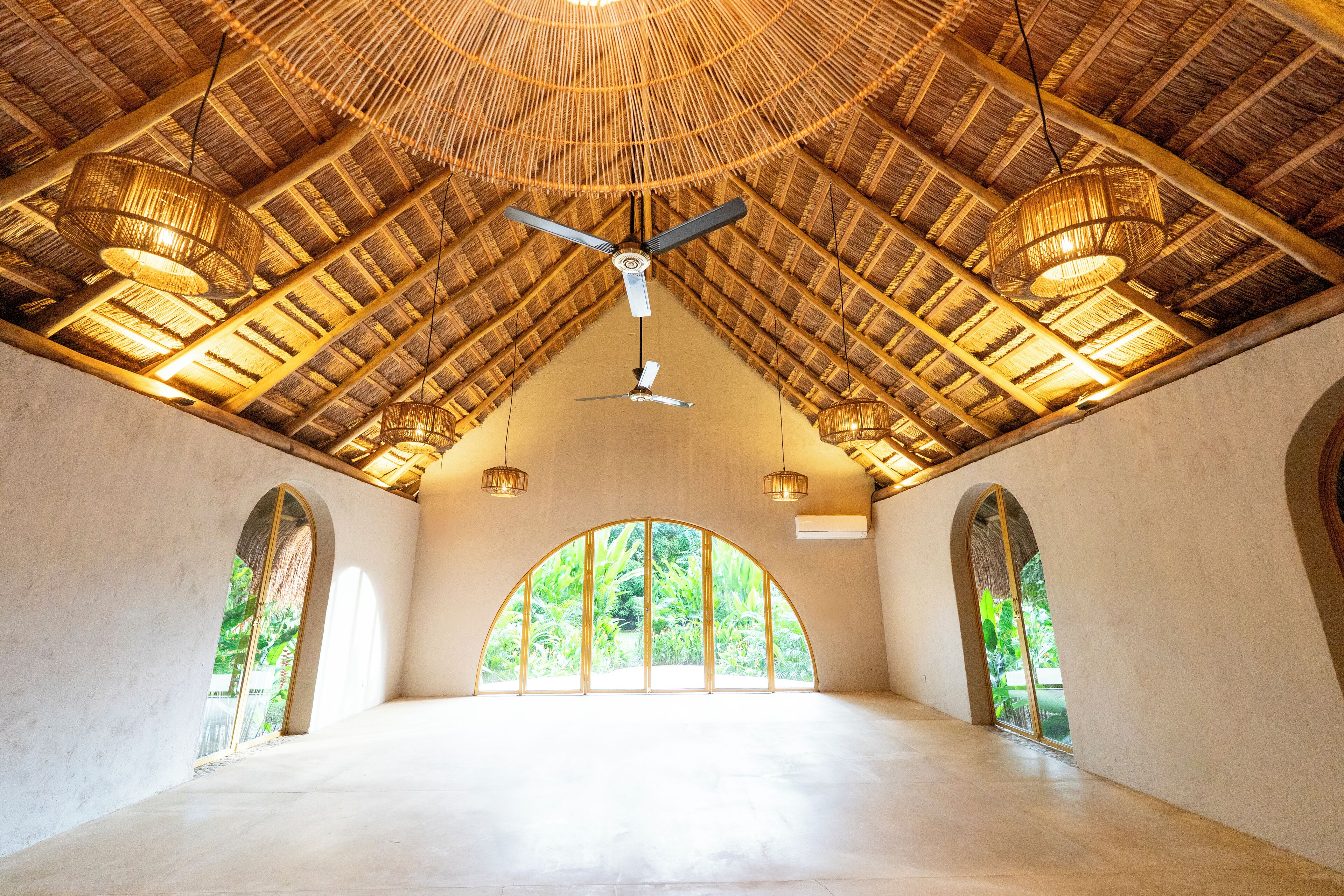 A spacious room with a high ceiling, large windows, and a ceiling fan.
