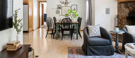 Un grand espace de vie comprenant une table à manger, des chaises, une cheminée et un téléviseur.