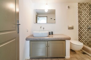 A bathroom with a white sink, a mirror, a toilet, and a shower area. - 10 meters from the Beach! (Perissa)