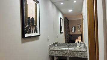 A modern bathroom with a granite countertop sink, a framed picture of a train, and a mirror.