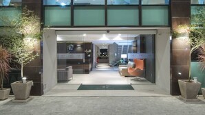 Un bâtiment moderne doté d’une façade en verre, d’un espace d’accueil avec un comptoir et des chaises, et de plantes en pot.