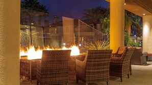 Eine Terrasse mit Korbstühlen und einer Feuerstelle.